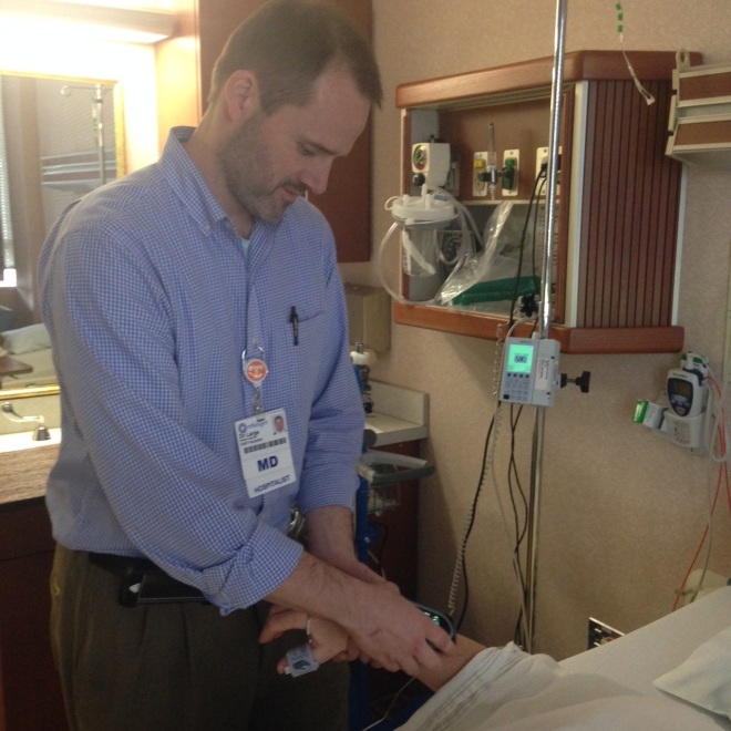Dr. Bradley Large, hospitalist at Erlanger East Hospital, checks the vital signs of a patient who is wearing the hospital’s new wireless monitor, known as ViSi Mobile System by Sotera Wireless.
