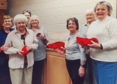 Volunteer knitters from Burks United Methodist Church with hand-made red hats that were donated to Erlanger’s newborn and NICU departments.